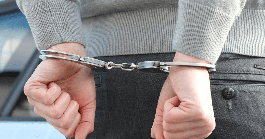 Plano de detalle de un joven detenido con las manos a la espalda y esposas metálicas tras los asaltos en El Ejido.